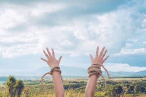woman hands with broken rope raised up to the sky over mountain landscape background, Christian praise and worship, freedom conceptual image