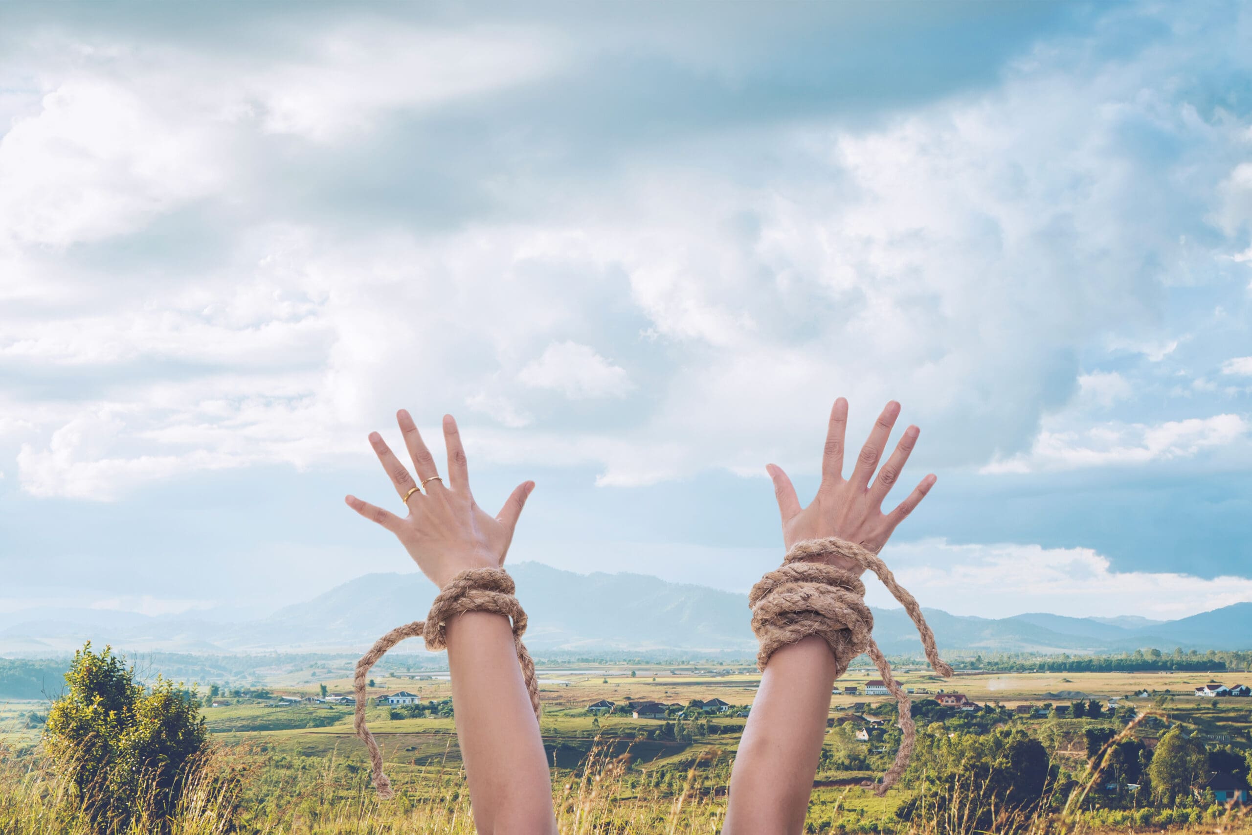 woman hands with broken rope raised up to the sky over mountain landscape background, Christian praise and worship, freedom conceptual image