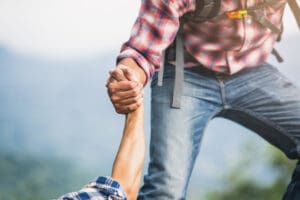 Helping hand outstretched for salvation . Strong hold. Couple hiking help each other in mountains . Two people climbing on mountain and helping.