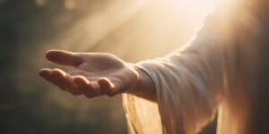 Jesus extends his hand in a moment of connection and guidance under soft light during a quiet setting
