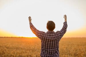 Man grateful for the harvest raised his hands up in the field