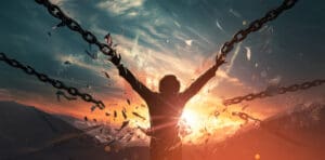 A person breaking chains at sunset, symbolizing freedom and liberation from burdens