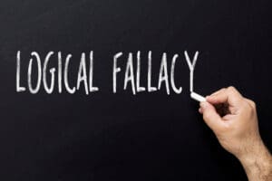 Hand writing logical fallacy text on blackboard
