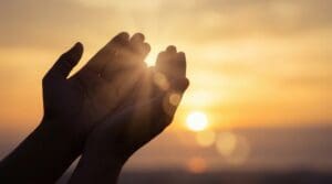 Human Hands Praying Towards the Sun with Beautiful Light Rays